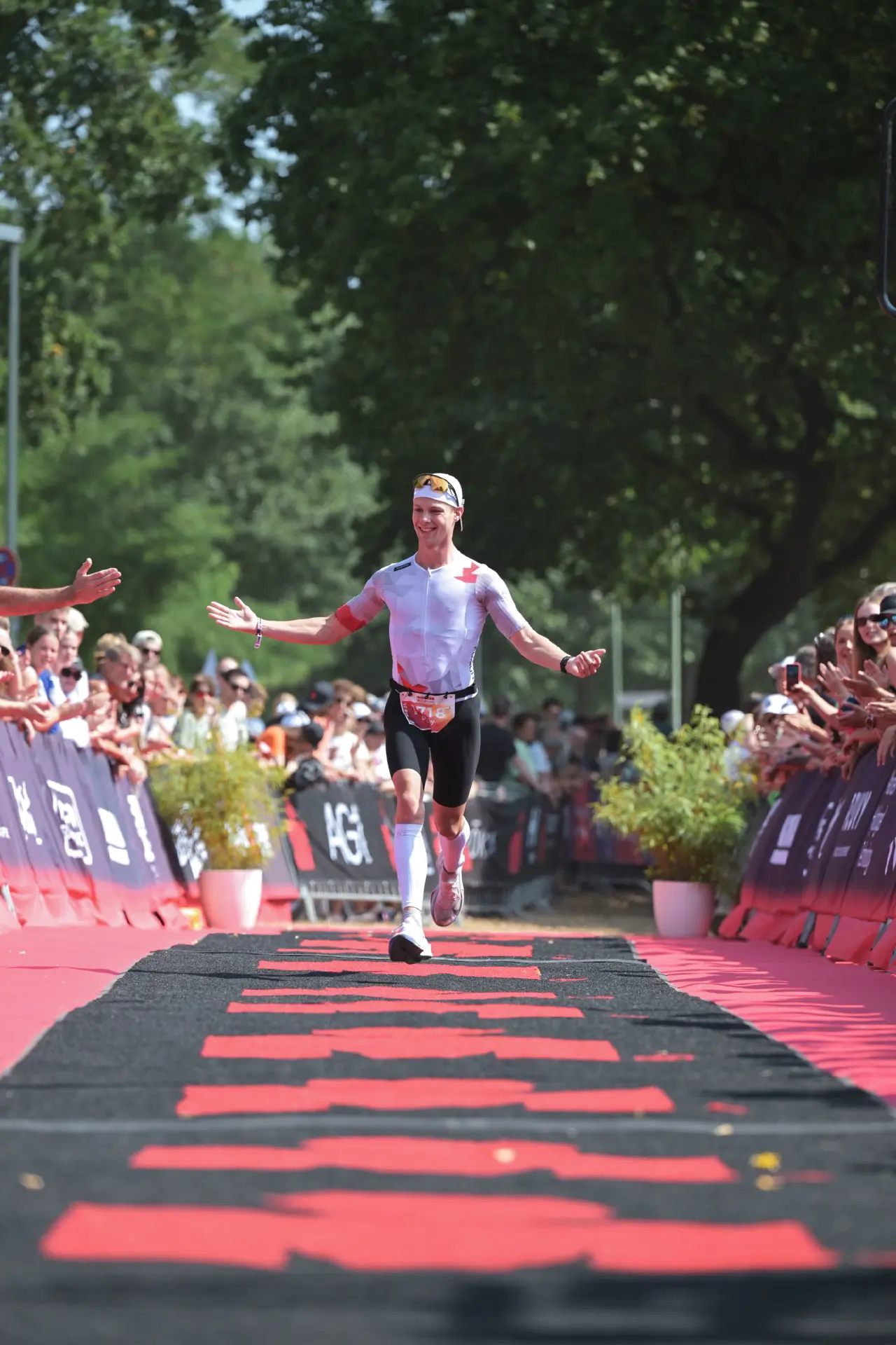 Danny Verdel with arms open, high-fiving the crowd on the finish carpet of Ironman 70.3 Duisburg 2026