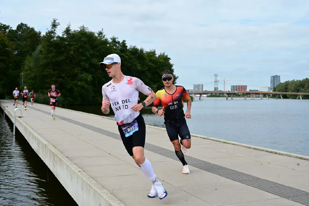 Danny Verdel loopt over een kade langs het water, gevolgd door een andere atleet, tijdens Challenge Almere-Amsterdam 2026