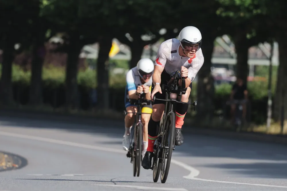 Danny Verdel riding ahead of another athlete on a tree-lined road during Ironman Frankfurt 2026