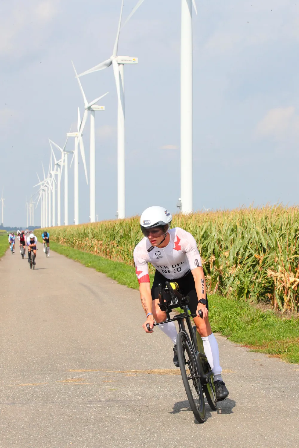 Danny Verdel fietst langs een rij windmolens en een maisveld tijdens Challenge Almere-Amsterdam 2026