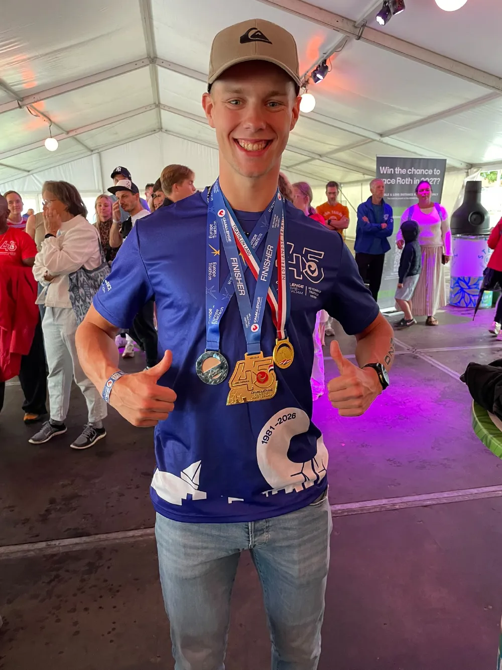 Danny Verdel steekt twee duimen op met de finisher- en kampioensmedailles na Challenge Almere-Amsterdam 2026